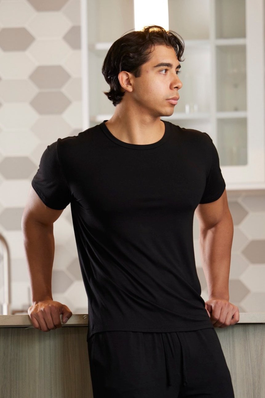 Man wearing a black t-shirt and shorts in a kitchen setting