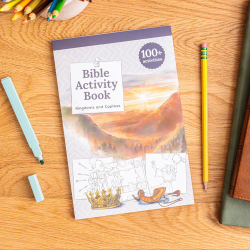 Bible Activity Book on a wooden table with pencils and a pen.