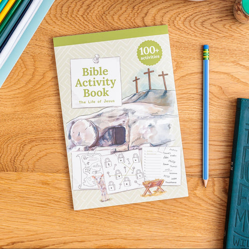 Bible Activity Book on a wooden surface with a pencil and other items.
