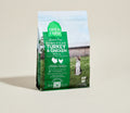 Green bag of Open Farm Homestead Turkey & Chicken recipe pet food on a beige background