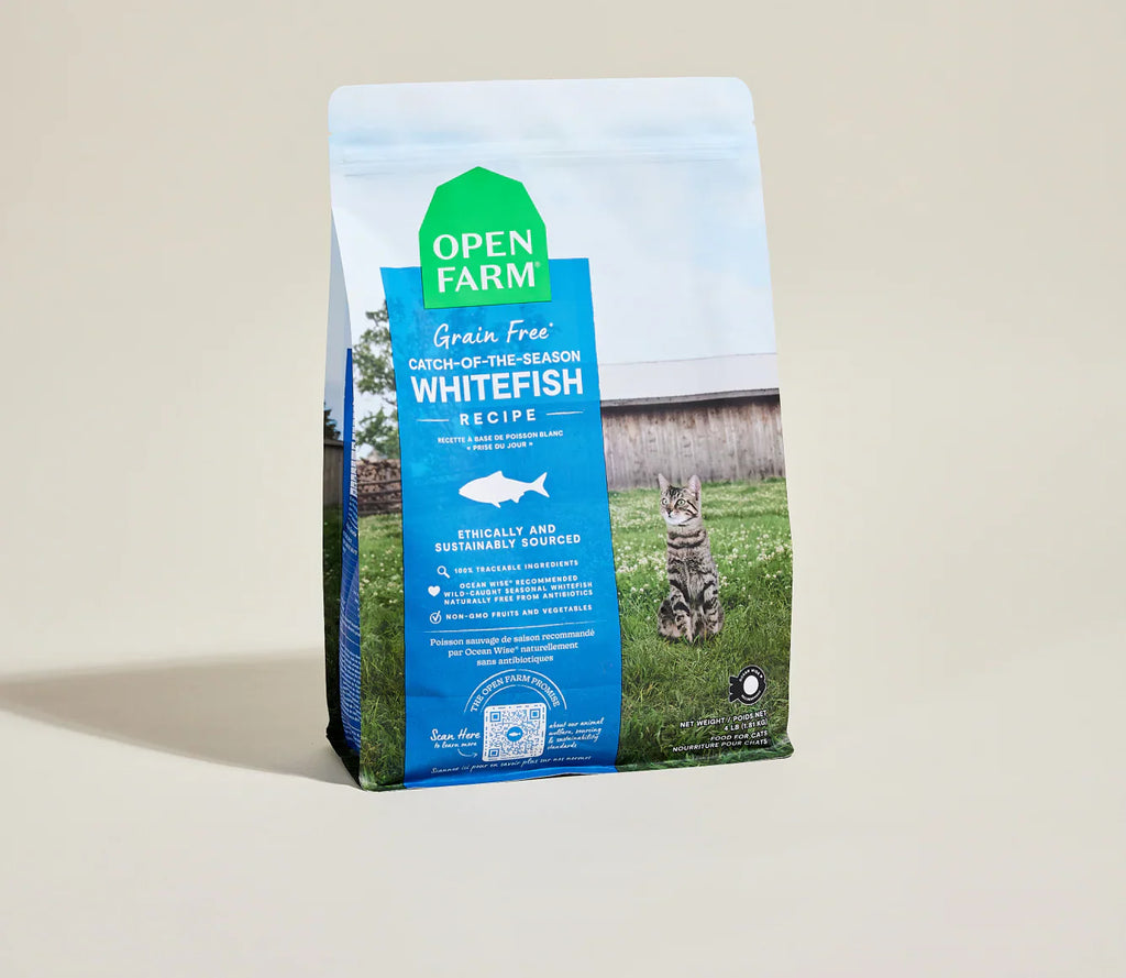 Bag of Open Farm cat food with a cat on a grassy field
