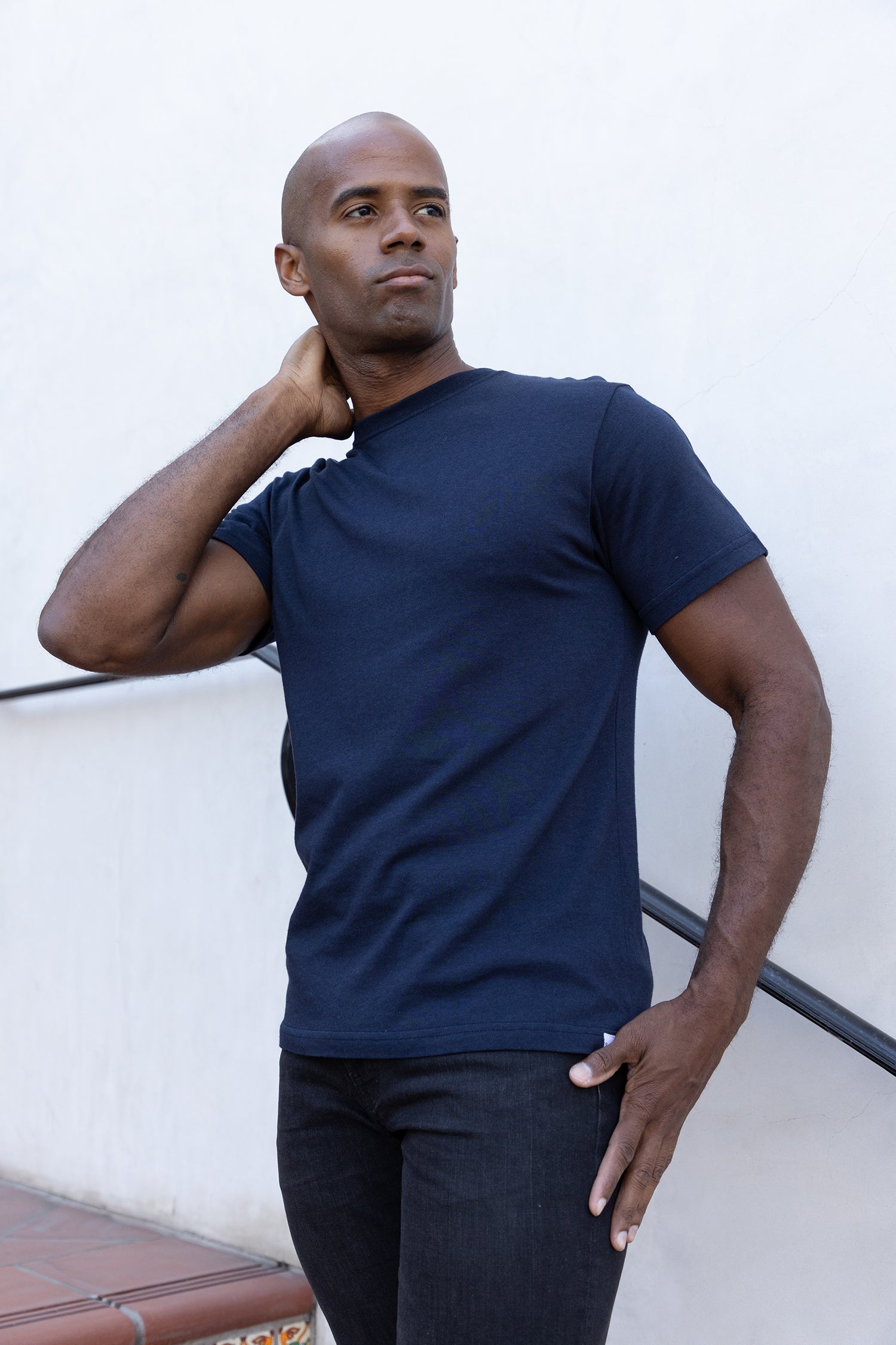 Man wearing a navy blue t-shirt against a white wall
