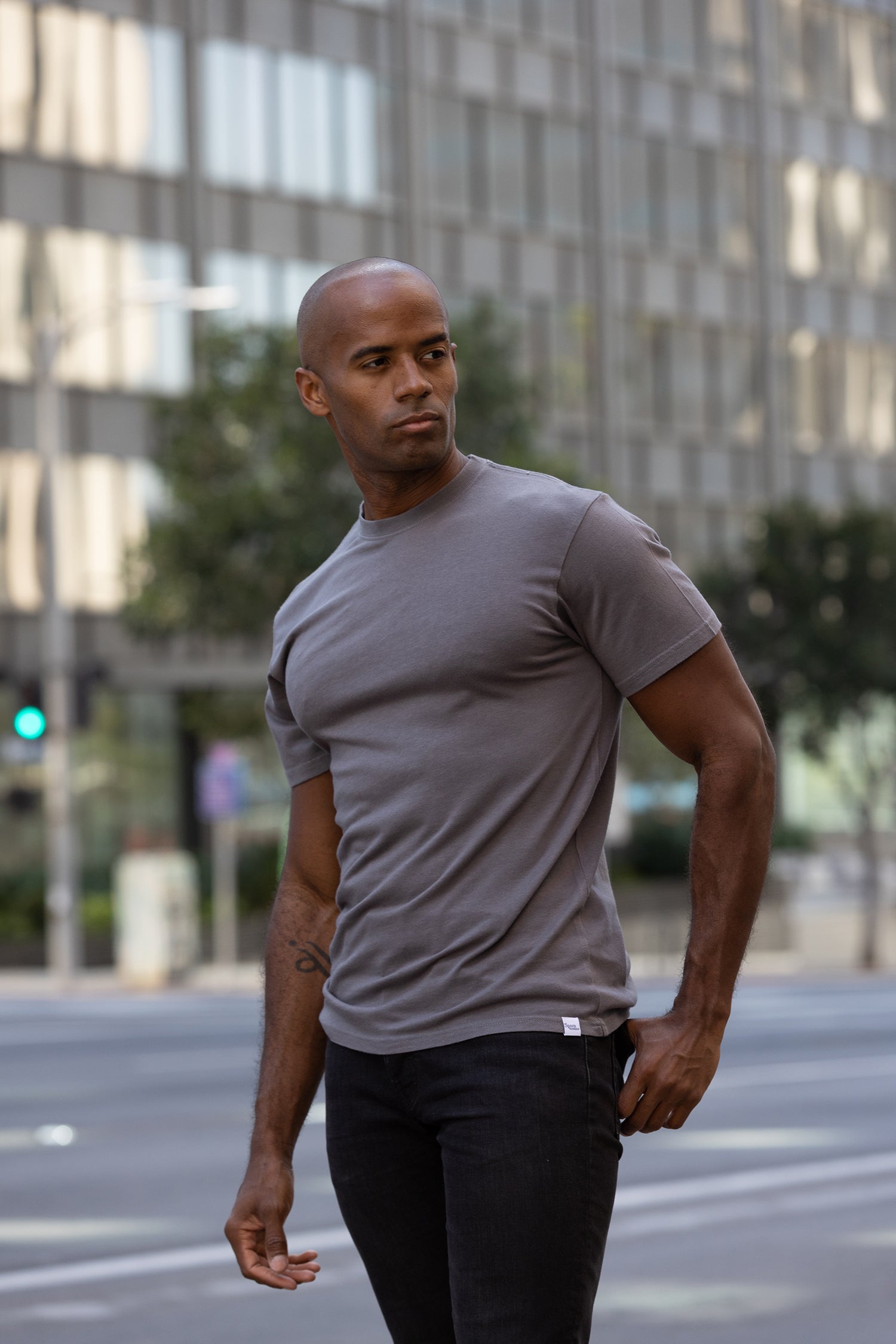 Man in a gray t-shirt and black pants walking on a city street.