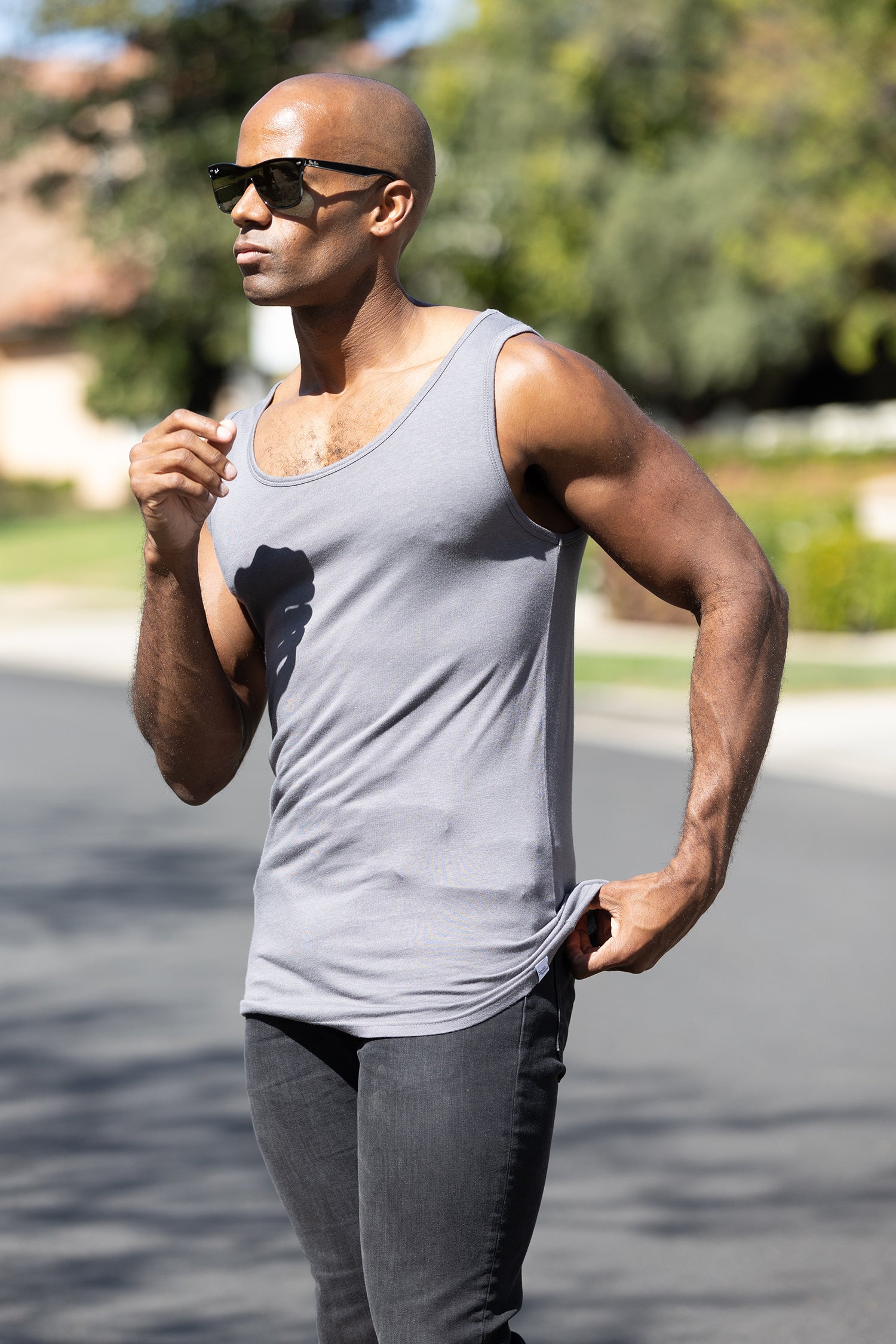Man wearing a gray tank top and sunglasses outdoors