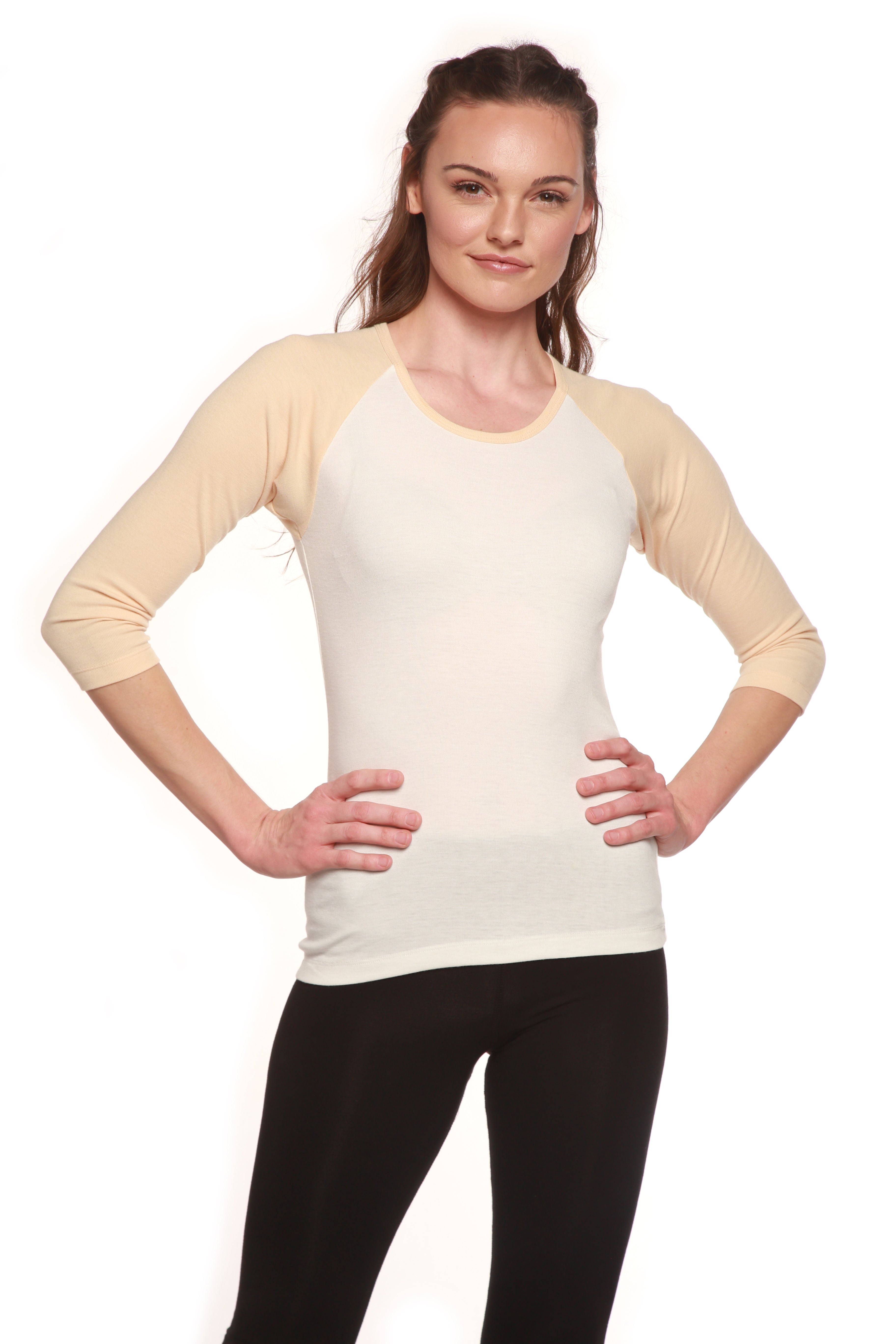 Woman wearing a cream long-sleeve top with black pants on a white background