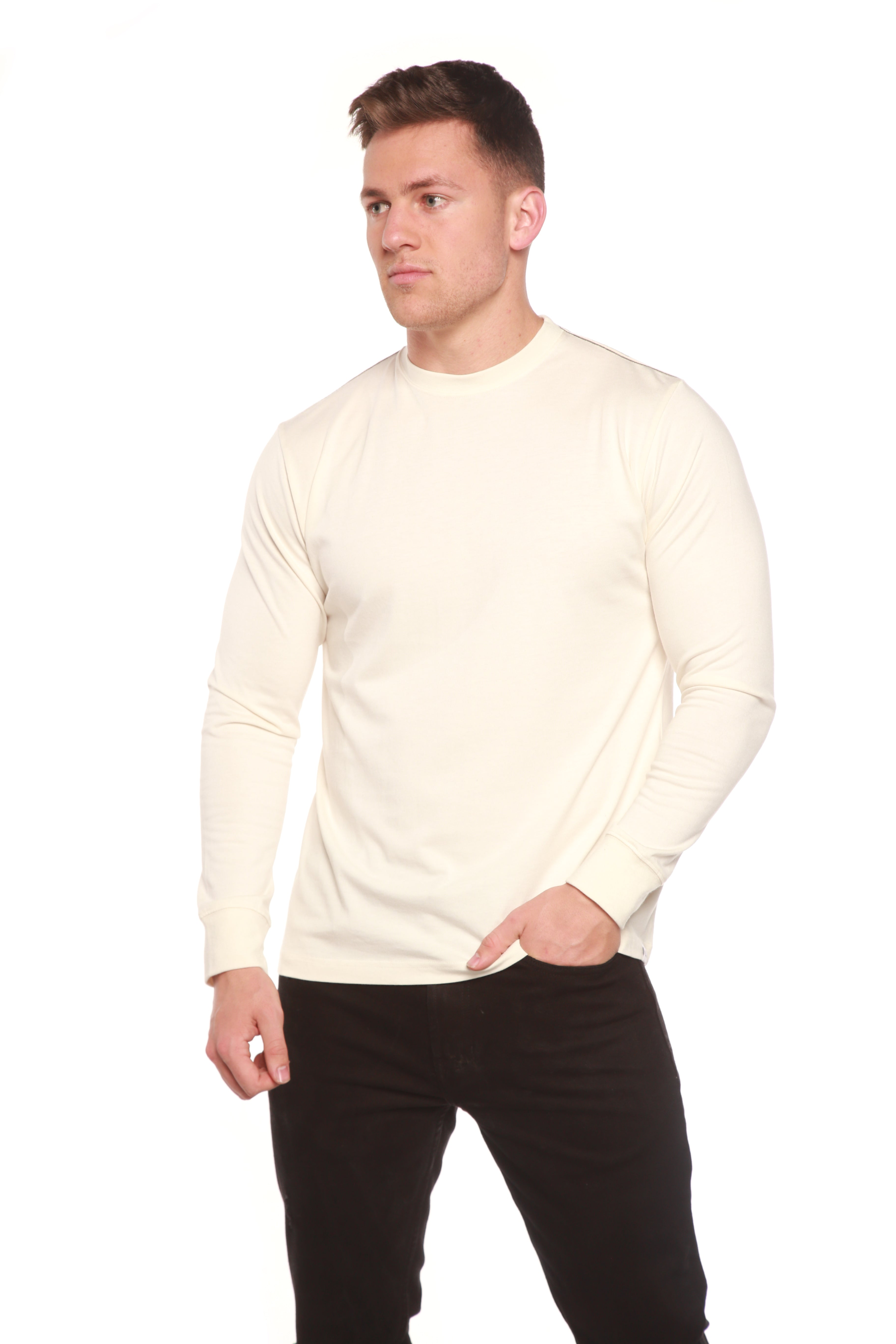 Man wearing a cream sweater and black pants on a white background