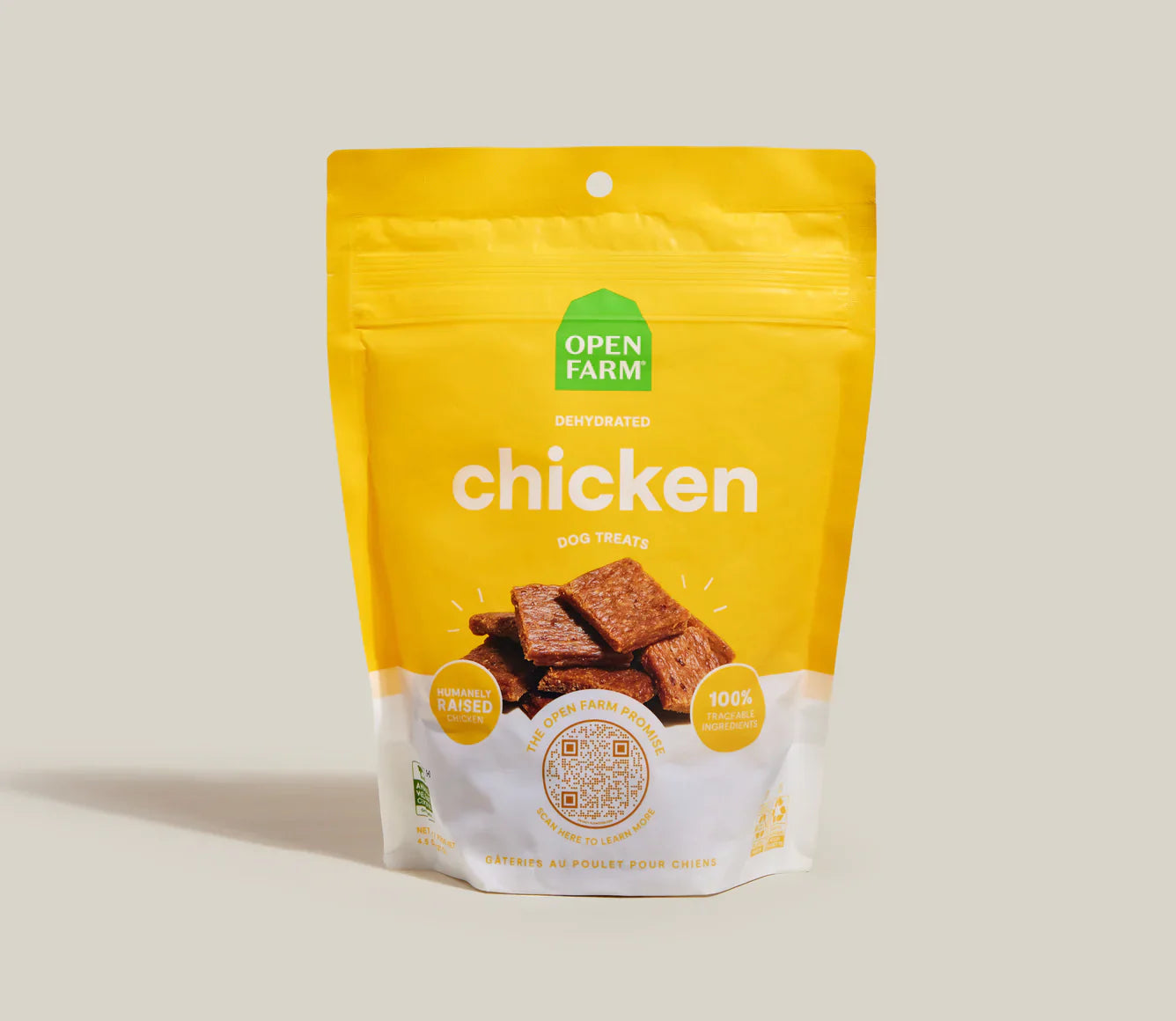 Yellow package of Open Farm chicken jerky on a beige background