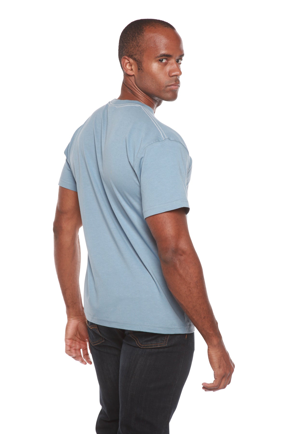 Man wearing a light blue t-shirt and dark pants on a white background