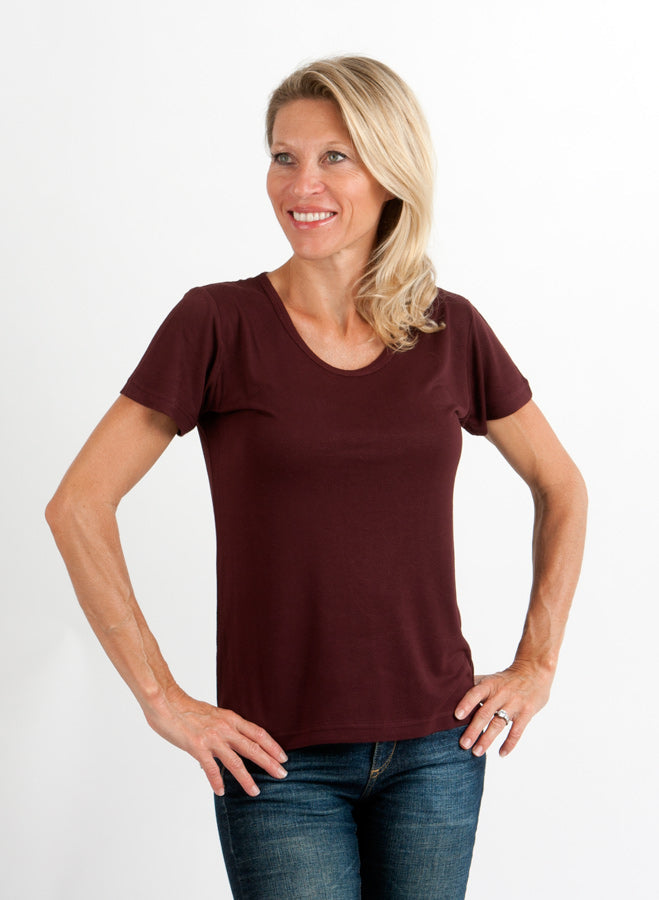 Woman wearing a maroon t-shirt and blue jeans on a white background
