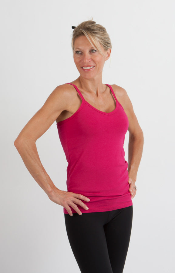 Woman wearing a pink tank top and black leggings on a white background