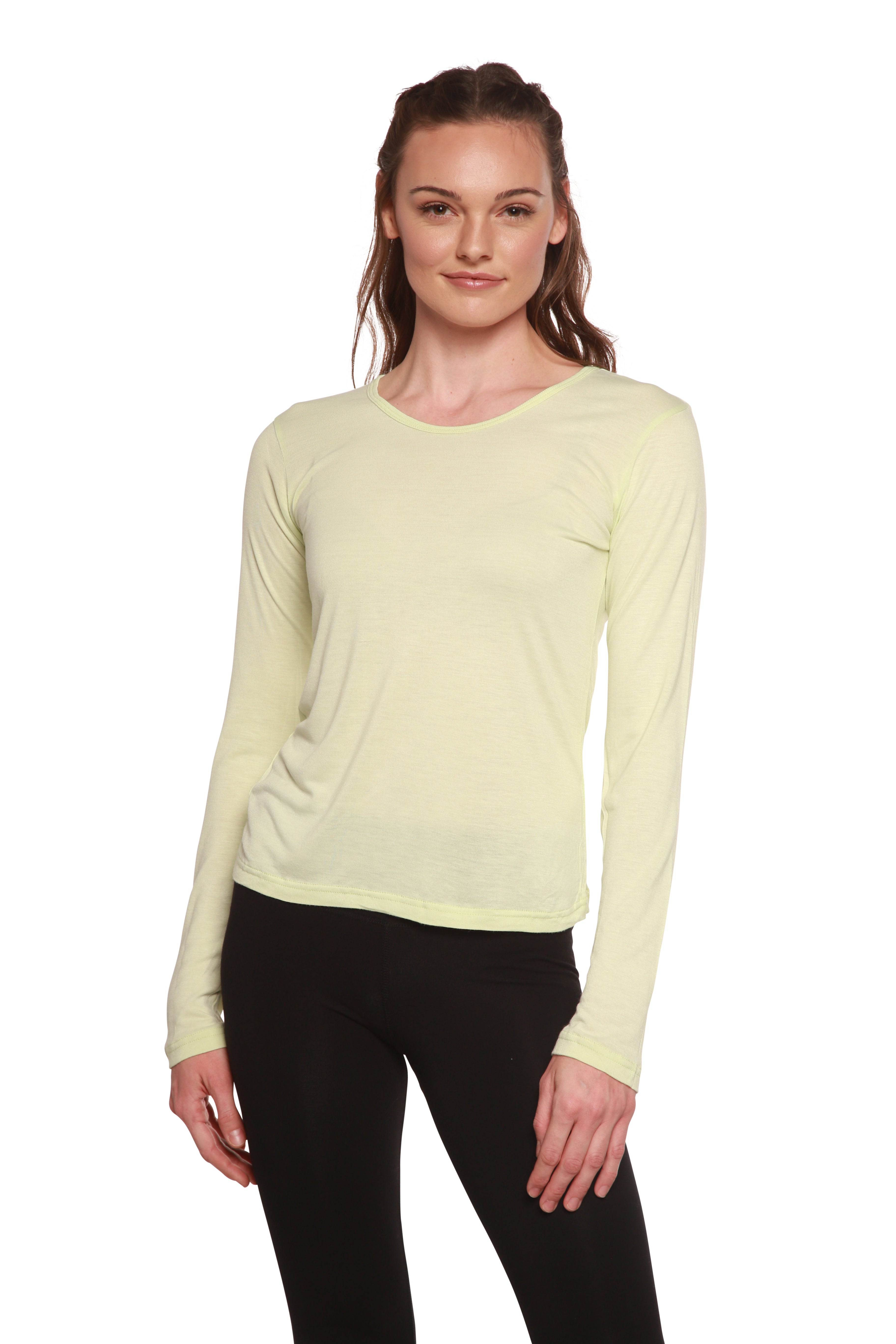 Woman wearing a light yellow long-sleeve top and black pants on a white background