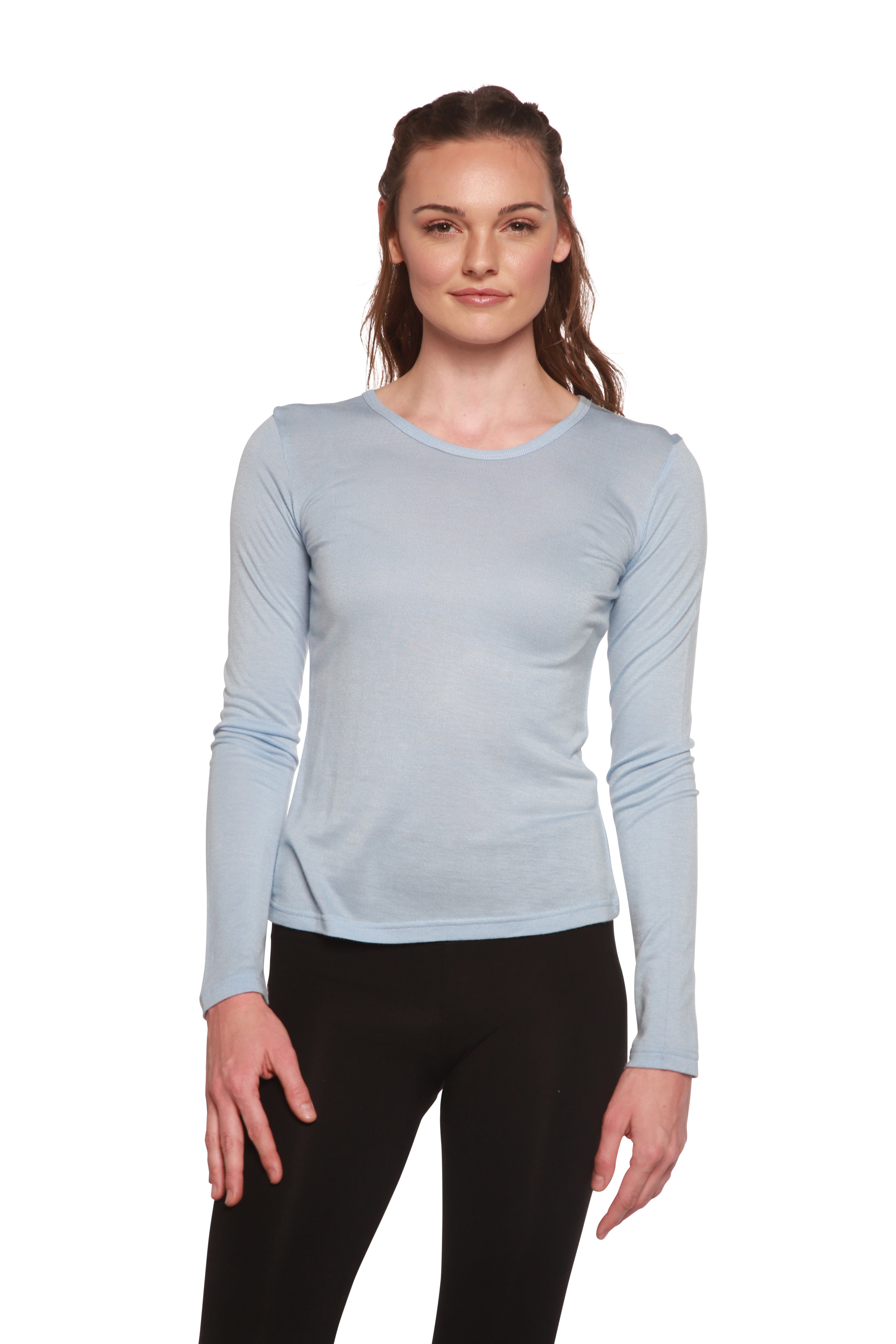 Woman wearing a light blue long-sleeve top and black pants on a white background